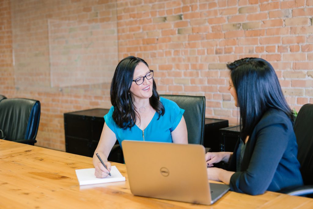 Woman in t-shirt sitting beside woman in suit jacket